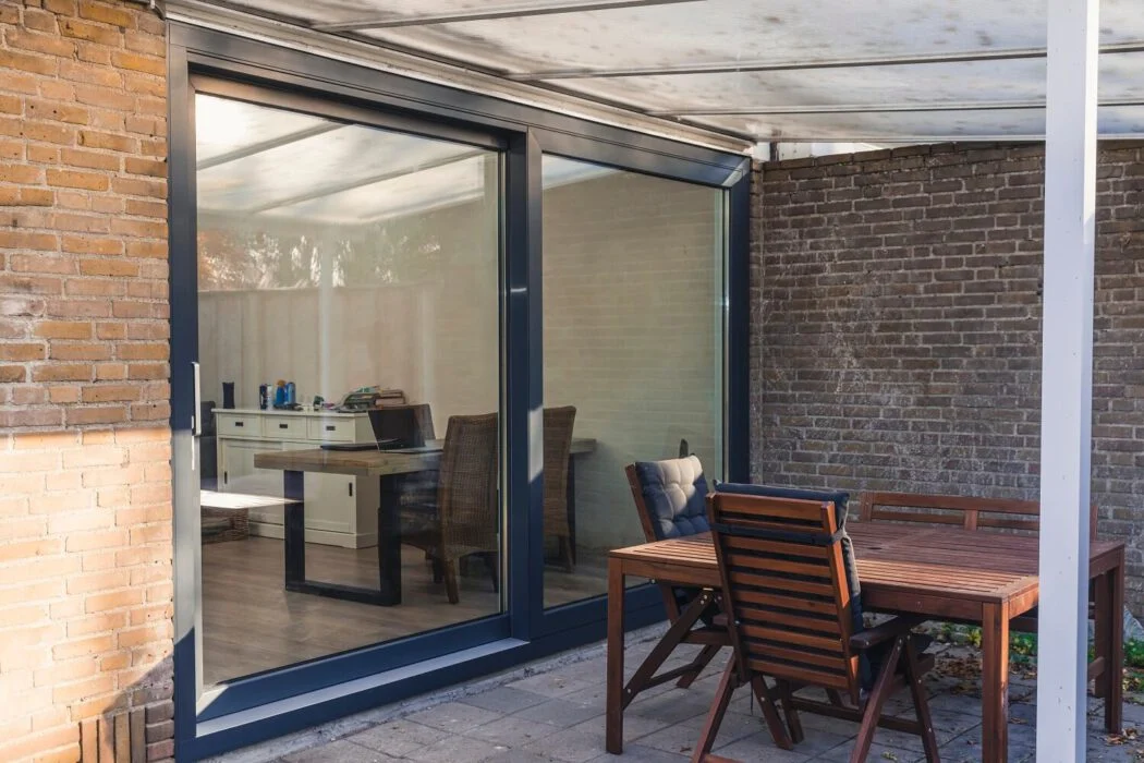 Aluminium schuifpui met grote glaspartij voor optimale lichtinval en strakke afwerking tussen binnen- en buitenruimte – Toelevering Online